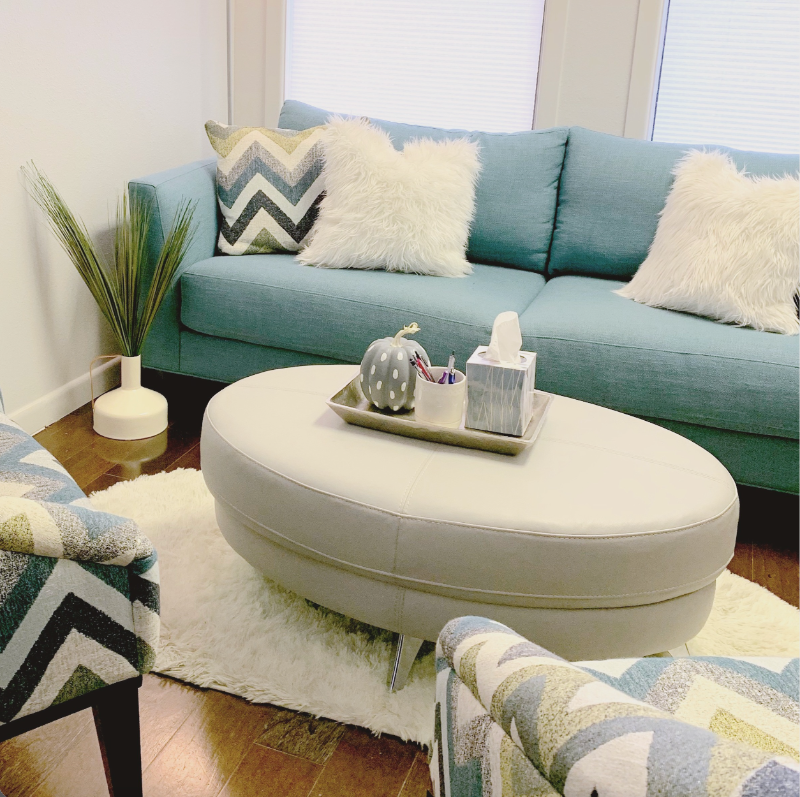 Susan Gonzales & Associates Counseling Office Space 2 One of Susan Gonzales and Associates Counseling's office spaces. This room includes a blue couch, ottoman, patterned chairs, and plant.