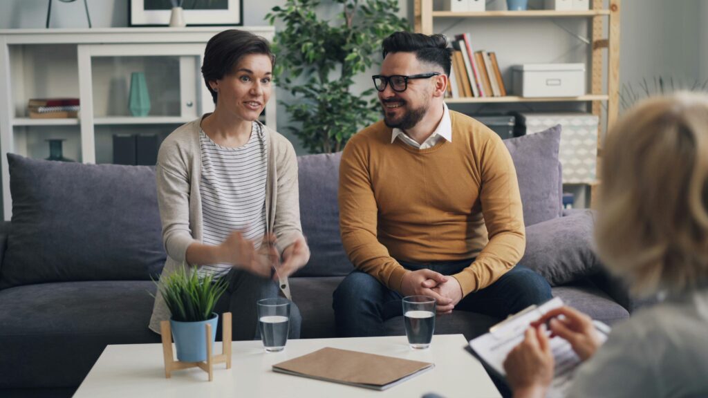 couple setting in therapy office looking at each other smiling